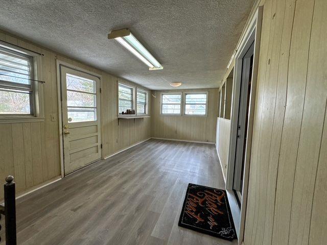 interior space featuring hardwood / wood-style floors, a textured ceiling, and wooden walls