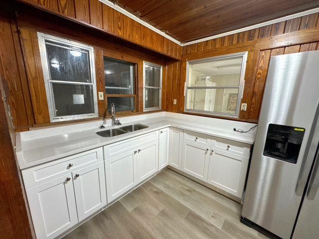 kitchen with white cabinets, sink, stainless steel refrigerator with ice dispenser, light wood-type flooring, and wood ceiling