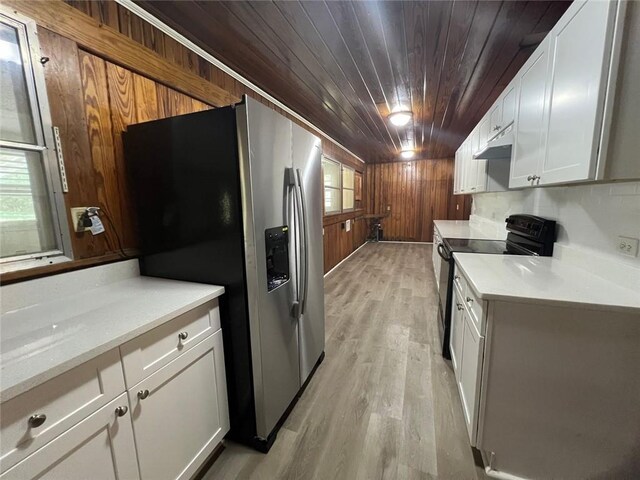 kitchen with stainless steel fridge, black electric range, white cabinets, and a healthy amount of sunlight