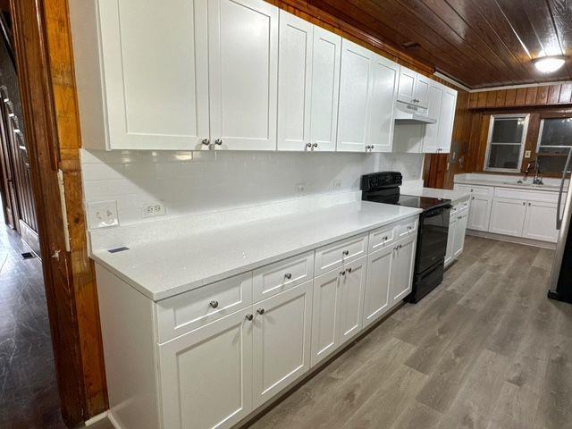 kitchen featuring wooden ceiling, sink, black electric range, white cabinetry, and wood-type flooring