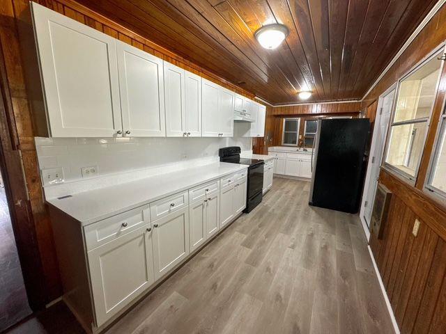 kitchen featuring wooden ceiling, white cabinets, black appliances, and light hardwood / wood-style floors