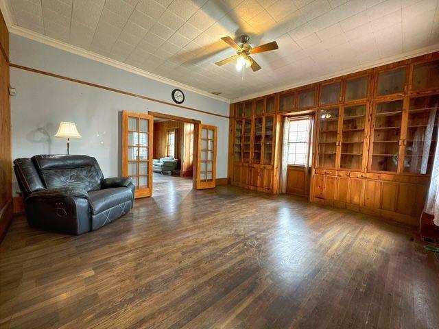 living room featuring crown molding, french doors, ceiling fan, and dark wood-type flooring