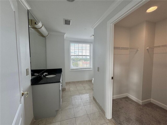 interior space featuring toilet, tile patterned flooring, vanity, and ornamental molding