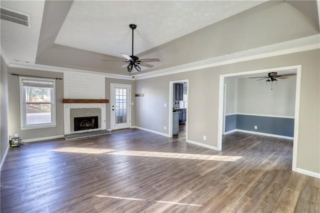 unfurnished living room with a raised ceiling, dark hardwood / wood-style floors, a fireplace, and ceiling fan