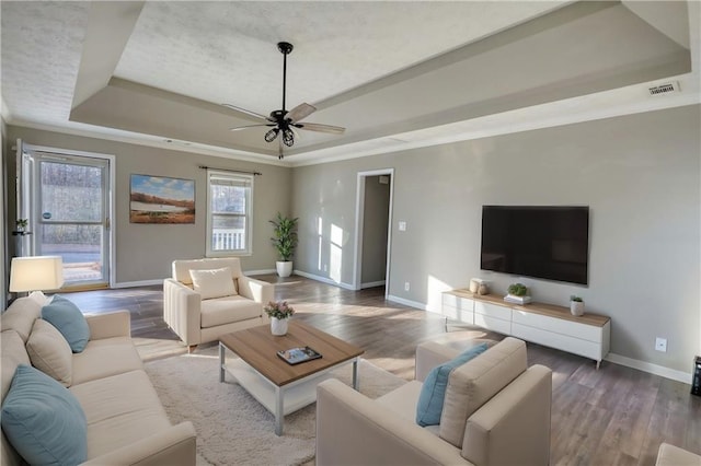 living room with crown molding, ceiling fan, a tray ceiling, and hardwood / wood-style floors