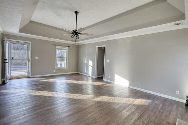 spare room with a raised ceiling, crown molding, dark wood-type flooring, and ceiling fan