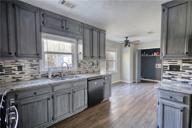 kitchen with sink, backsplash, black dishwasher, light stone counters, and dark hardwood / wood-style flooring