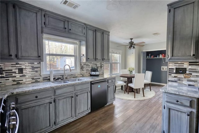 kitchen with dark wood-type flooring, black dishwasher, sink, and backsplash