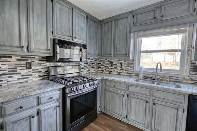 kitchen featuring light stone counters, sink, decorative backsplash, and black appliances