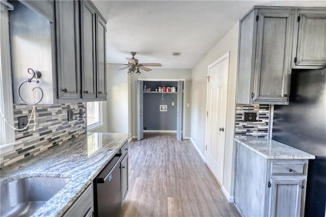 kitchen featuring light hardwood / wood-style flooring, ceiling fan, black refrigerator, light stone countertops, and stainless steel dishwasher