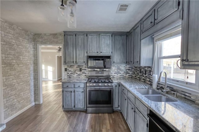 kitchen with sink, hardwood / wood-style floors, light stone counters, and black appliances