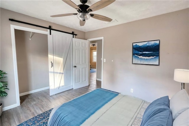 bedroom featuring a barn door, light wood-type flooring, and ceiling fan