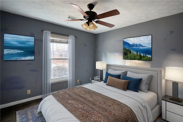 bedroom with dark wood-type flooring, a textured ceiling, and ceiling fan