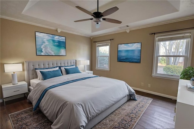 bedroom featuring dark hardwood / wood-style flooring, ceiling fan, and a tray ceiling