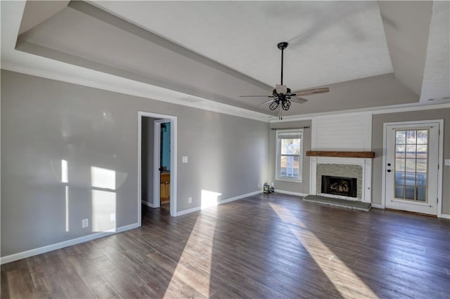 unfurnished living room featuring plenty of natural light, a tray ceiling, and dark hardwood / wood-style flooring