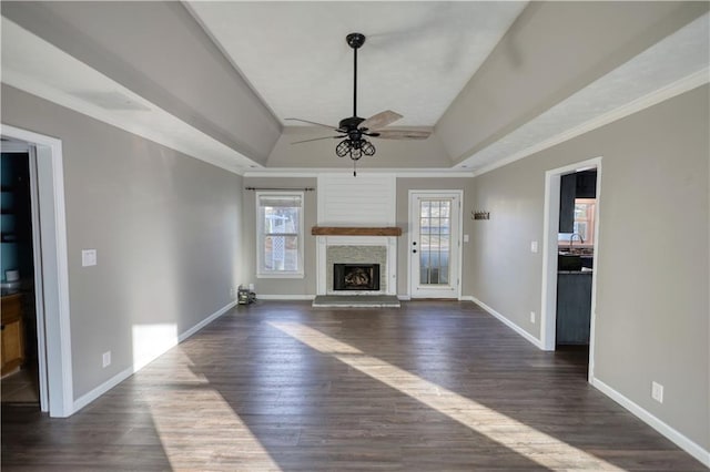 unfurnished living room with a fireplace, a tray ceiling, dark wood-type flooring, and ceiling fan