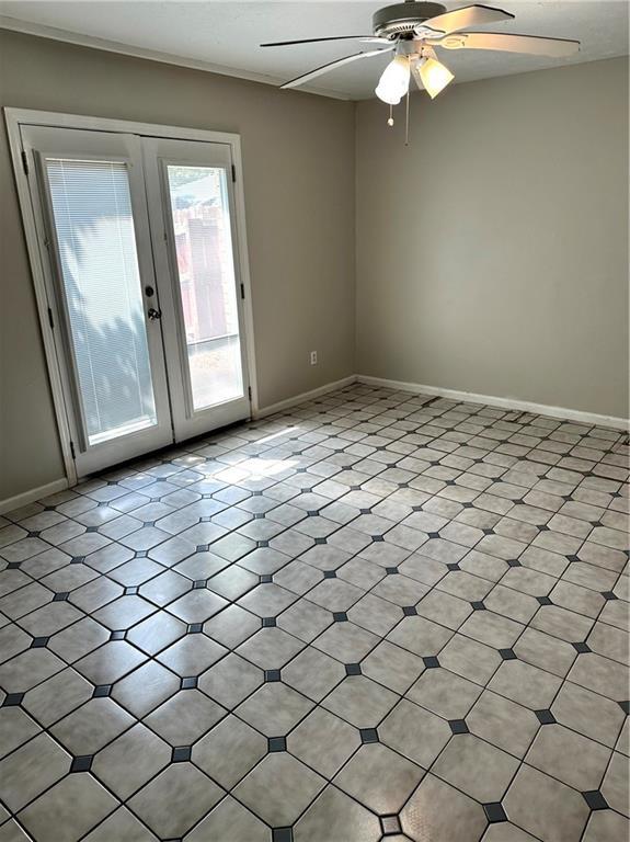 spare room with french doors, a ceiling fan, and baseboards