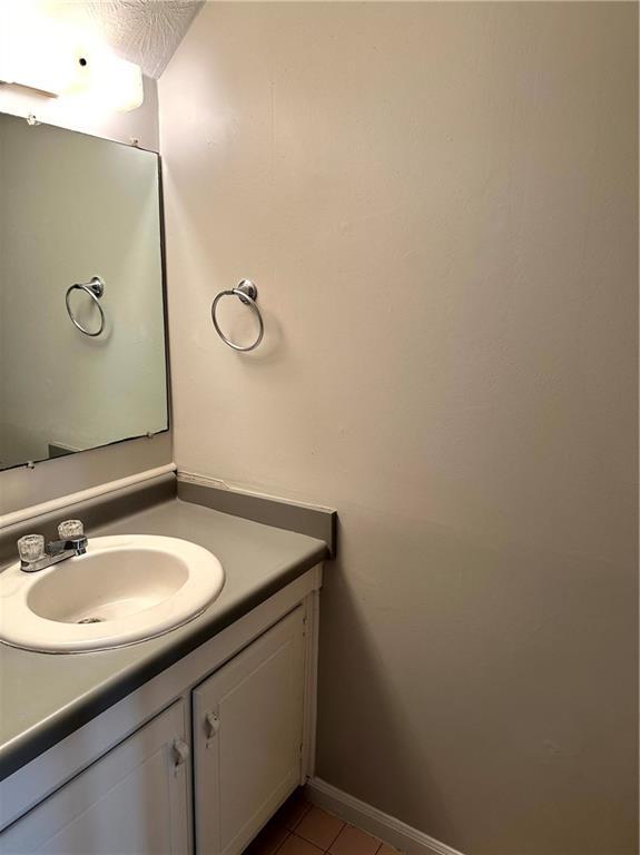 bathroom with vanity, baseboards, and tile patterned floors