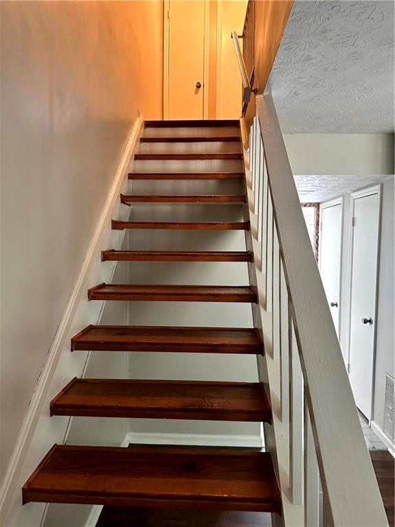 stairs featuring a textured ceiling