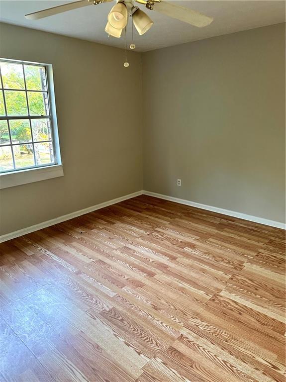 spare room featuring ceiling fan, baseboards, and light wood-type flooring