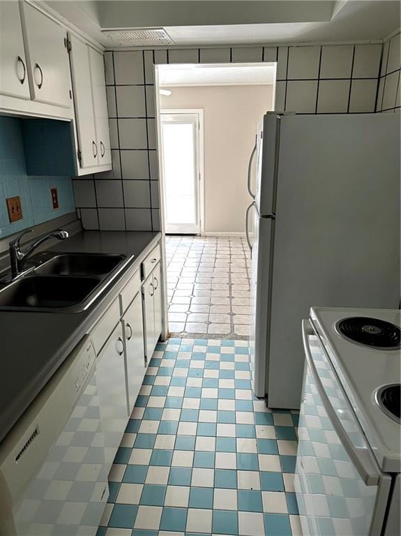 kitchen featuring a sink, white cabinetry, backsplash, and white appliances
