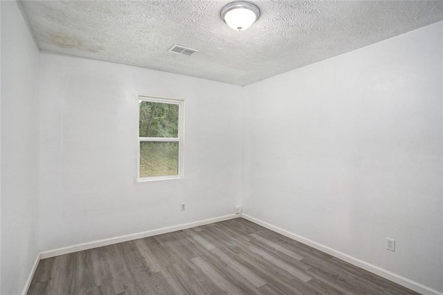 empty room with hardwood / wood-style flooring and a textured ceiling