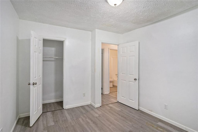 unfurnished bedroom featuring a textured ceiling, a closet, and light wood-type flooring