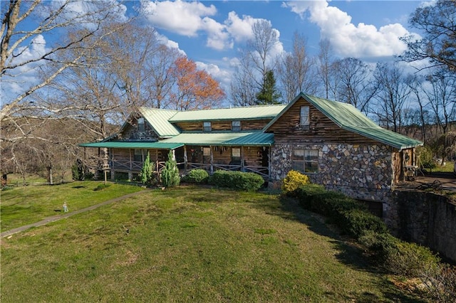 back of house featuring covered porch, metal roof, a lawn, and stone siding