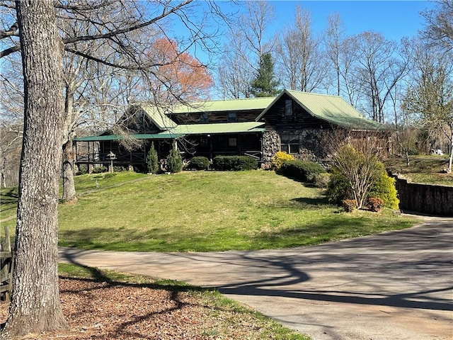 view of home's exterior featuring driveway, metal roof, and a yard