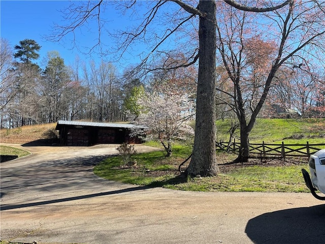 view of yard featuring an outbuilding, driveway, and fence