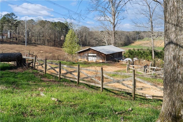 view of yard with a detached garage, fence, a pole building, a rural view, and an outdoor structure