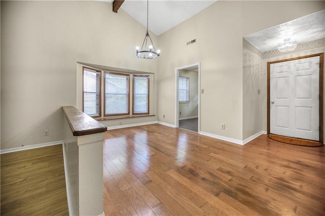 foyer with a notable chandelier, hardwood / wood-style flooring, high vaulted ceiling, and beamed ceiling