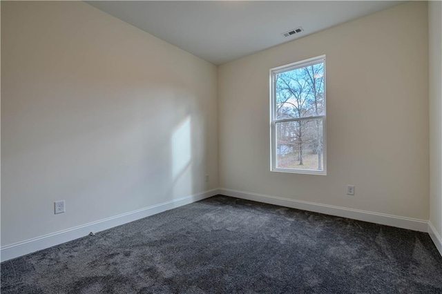 spare room featuring dark carpet