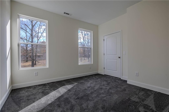 unfurnished room with plenty of natural light and dark colored carpet