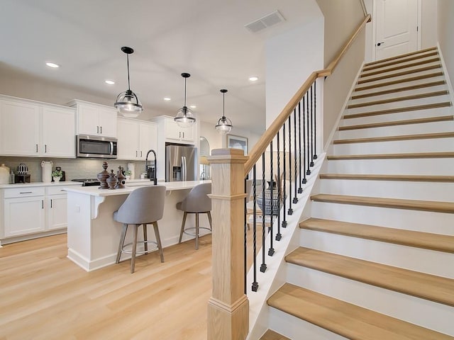 3350 Cranston Ln, Kennesaw, GA 30144 - kitchen with appliances with stainless steel finishes, recessed lighting, light wood-type flooring, tasteful backsplash, and a kitchen bar