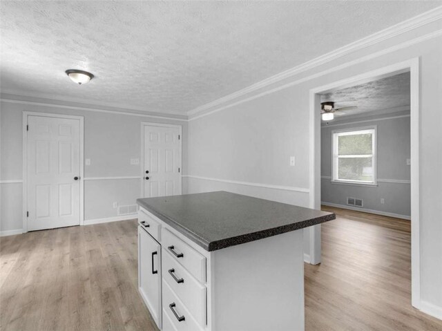 4720 Hull Rd, Conyers, GA 30094 - kitchen featuring a textured ceiling, dark countertops, a center island, light wood finished floors, and white cabinets
