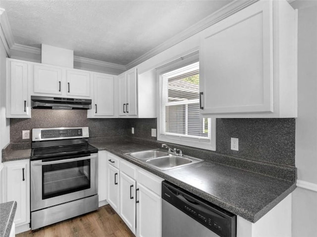 4720 Hull Rd, Conyers, GA 30094 - kitchen featuring appliances with stainless steel finishes, under cabinet range hood, crown molding, dark countertops, and white cabinetry