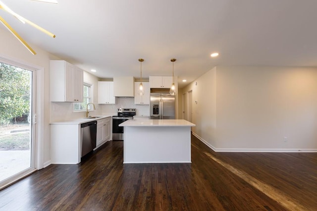 kitchen featuring dark wood-type flooring, light countertops, white cabinets, stainless steel appliances, and a sink