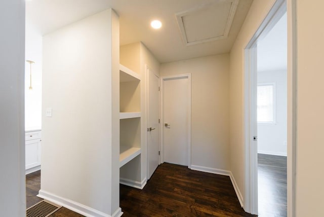 hall with visible vents, attic access, baseboards, and dark wood-style flooring