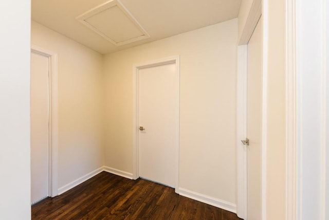 unfurnished room with baseboards, attic access, and dark wood-style flooring