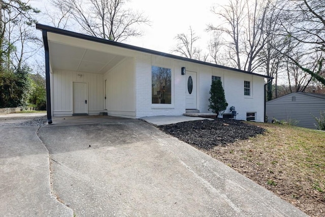 view of front of home with brick siding, concrete driveway, and a carport