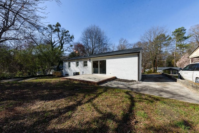 back of house featuring a lawn and brick siding