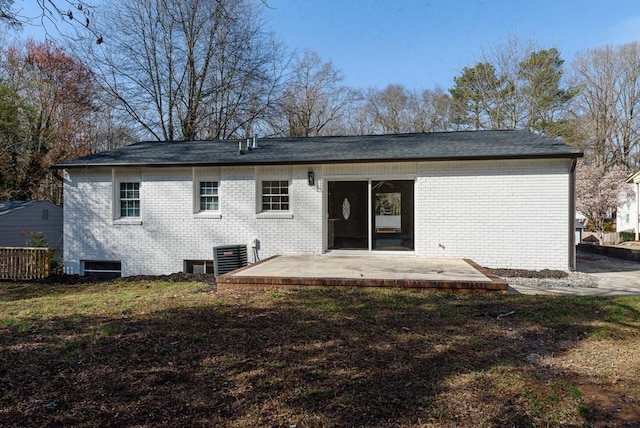 rear view of house with central air condition unit, brick siding, a yard, and a patio area