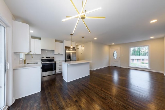 kitchen featuring a kitchen island, dark wood finished floors, a sink, white cabinets, and appliances with stainless steel finishes