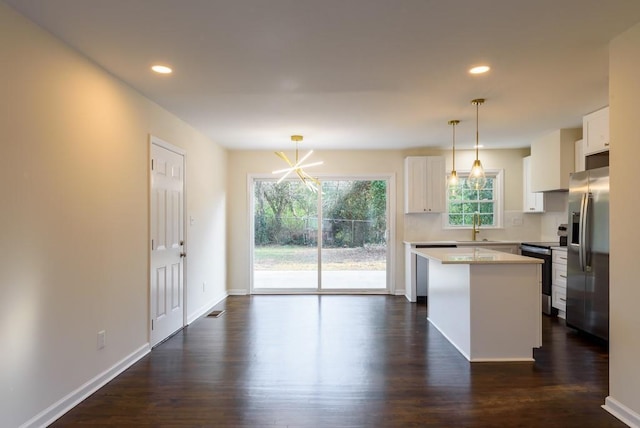 kitchen featuring a kitchen island, dark wood finished floors, a sink, appliances with stainless steel finishes, and white cabinetry