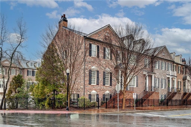 exterior space with brick siding, a fenced front yard, and a chimney