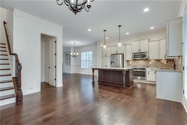 kitchen featuring a kitchen island, decorative light fixtures, sink, a chandelier, and stainless steel appliances