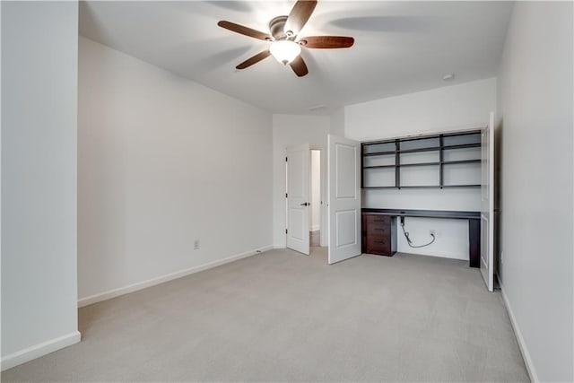 unfurnished bedroom featuring ceiling fan, built in desk, and light carpet