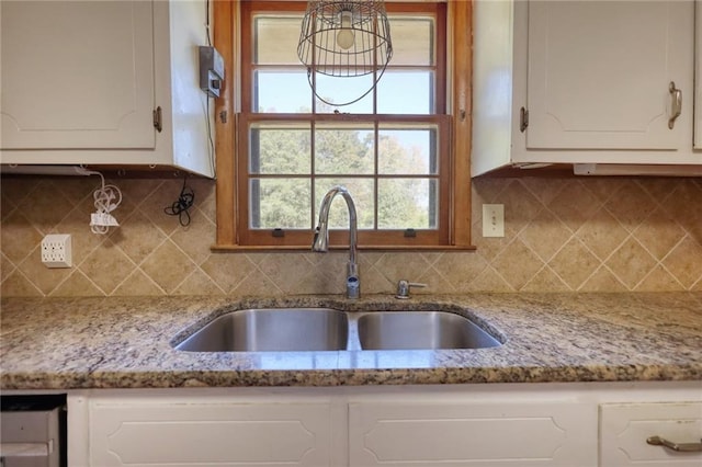 kitchen featuring tasteful backsplash, white cabinetry, sink, and light stone countertops