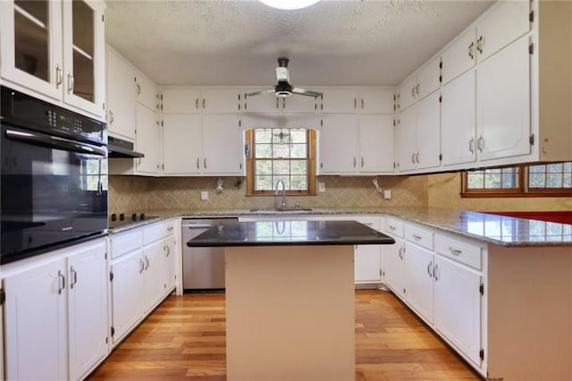 kitchen featuring white cabinetry, dishwasher, a center island, sink, and black oven